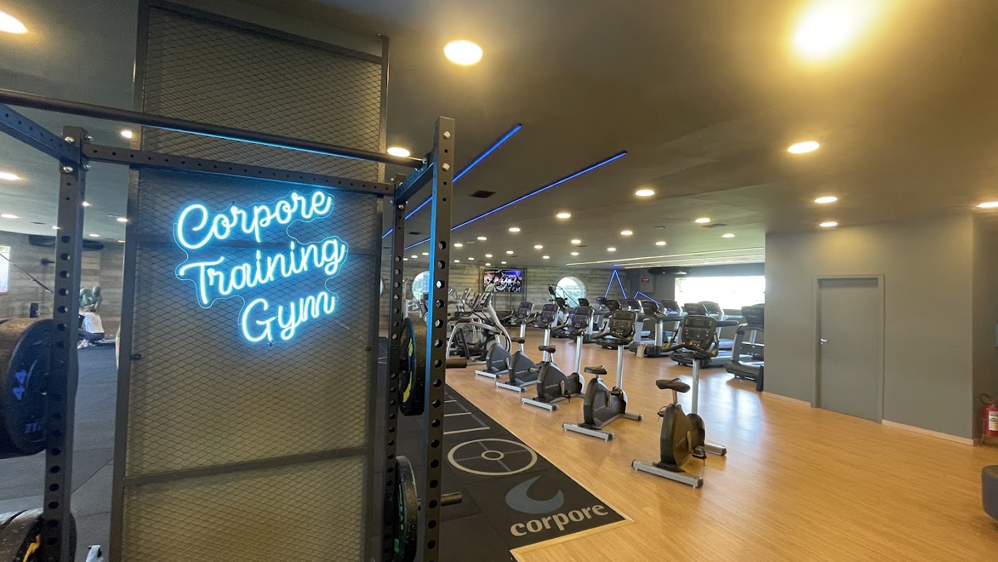 Área Corpore Training Gym em neon com bikes e esteiras